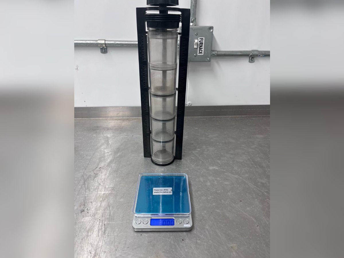 A robot is standing in front of a glass cylinder.